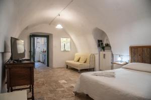法萨诺Masseria Trotta B&B的一间卧室配有一张床、一台电视和一把椅子