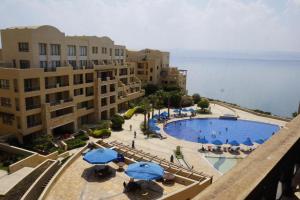 索瓦马Spacious apartments with Sea view at Samarah Resort的享有带遮阳伞和建筑的游泳池的景色