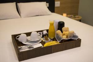 阿雷格里港Taikô Motel by Drops的床上的托盘,上面有食物和餐具