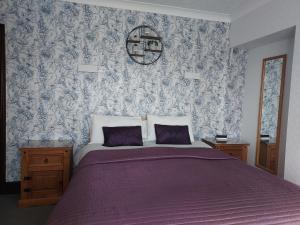 大雅茅斯马璐斯旅馆的一间卧室配有一张带紫色床罩和壁纸的床。