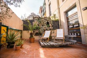 巴塞罗那360 Hostel Borne的两把椅子坐在种有植物的庭院里
