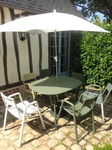 Montreuil-en-CauxLe Clos-Masure de Béatrice的庭院里配有桌椅和遮阳伞