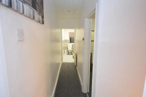巴尔金Lovely 3 Bedroom House near Barking Station的一条带白色墙壁的走廊和一个带门的走廊