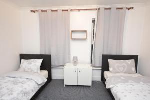 巴尔金Lovely 3 Bedroom House near Barking Station的一间卧室设有两张床和窗户。