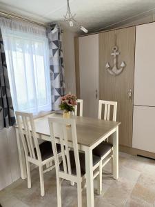 纽基Mollys Retreat pet friendly three bed caravan with small garden Newquay Bay Resort Quieter area of park的厨房配有木桌、椅子和窗户。