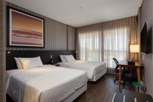 伊达贾伊Hilton Garden Inn Praia Brava的酒店客房配有两张床和一张书桌