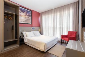 伊达贾伊Hilton Garden Inn Praia Brava的酒店客房,配有一张床和一张红色椅子