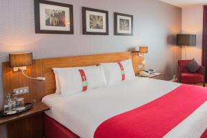 诺里奇假日诺威奇城市酒店的酒店客房设有一张大床和一张红色椅子。