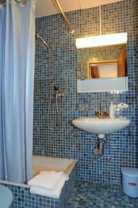 贝特默阿尔卑阿尔盆豪斯贝特默拉尔普酒店的蓝色瓷砖浴室设有水槽和淋浴