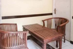 SewanRisqia Syariah TOD M1 Bandara Soekarno Hatta Mitra RedDoorz的一张木桌和两把椅子以及一张木凳