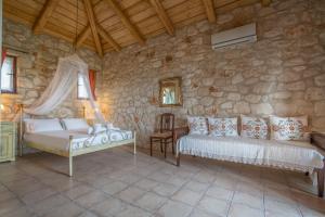 瓦西里科斯塔佩特里那米尔提斯石屋旅馆的一间卧室设有两张床和石墙