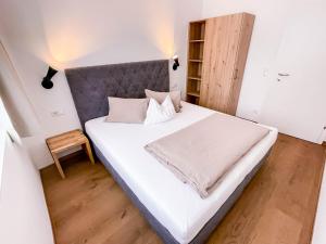 滕嫩山麓圣马丁Glüxplatzl Appartements am Wald的卧室配有一张白色大床和灰色床头板