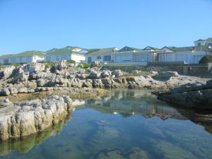 赫曼努斯Beachfront Cottage - Hermanus Whale View的河里,有些房子前面有岩石