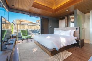 拉扬海滩度AKRA Collection Layan的一间卧室设有一张床,阳台配有电视。