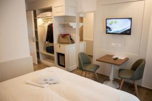 特里卡塞阿迪亚提克酒店的客房设有一张床、一张桌子和一个衣柜。