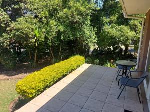 德班维尔Mimosa Self-Catering Studio Durbanville的一个带桌椅和灌木的庭院
