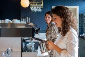 布雷达Boutique Hotel Het Scheepshuys的两名妇女站在带咖啡机的厨房