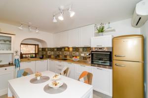杜布罗夫尼克Holiday Home Tezoro Royal的厨房配有白色橱柜、桌子和冰箱。