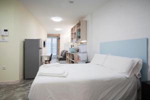 奥伦塞Apartamentos Turísticos As Burgas 6 by Bossh Hotels的卧室配有白色的床和冰箱。