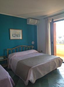 西尔米奥奈伊尔比安克斯皮诺旅馆的一间卧室配有一张蓝色墙壁的床和一扇窗户