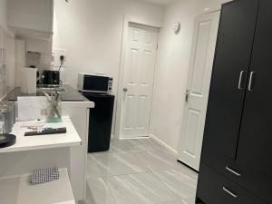 考文垂Elegant Practical onsite Cosy Studio in a quiet location的厨房配有黑冰箱和白色的台面