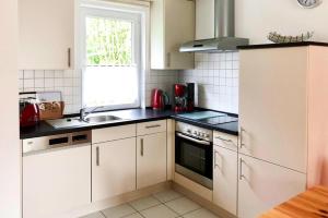 卢布明Semi-detached house, Lubmin的厨房配有白色橱柜、水槽和窗户。