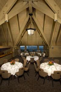 加文门特营山林小屋酒店的宴会厅配有白色的桌椅和吊灯