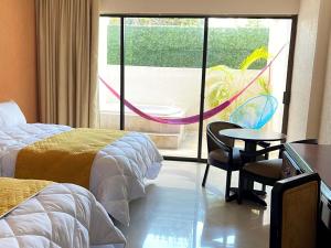 梅里达Hotel Los Aluxes的酒店客房带两张床和一张桌子以及椅子。