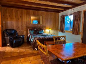 鲁伊多索West Winds Lodge的卧室配有1张床、1张桌子和1把椅子