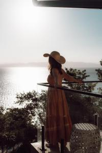 弗洛里亚诺波利斯Naatooh Guest Houses的戴帽子的女人站在一个俯瞰大海的阳台