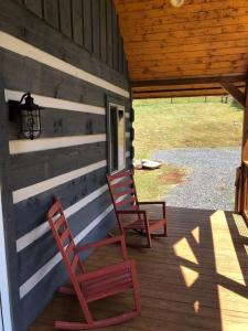 WhitetopCozy Cabin Near Grayson Highlands State Park的两个红色椅子坐在小屋的门廊上