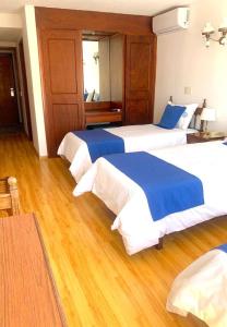 埃斯特角城阿尔罕布拉酒店的配有2张床的酒店客房,铺有木地板