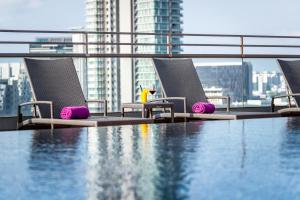 新加坡Hotel Traveltine的一个带椅子的游泳池,享有城市美景