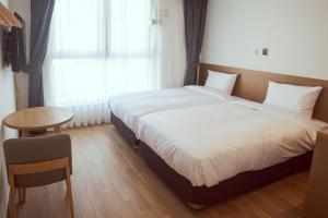 釜山Kenny Stay Busan Gijang的一间卧室配有一张床、一张桌子和一个窗户。