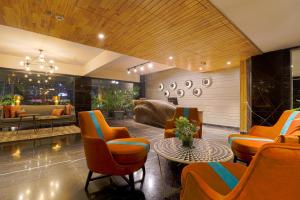古尔冈AIR by Ahuja Residences的客厅配有橙色椅子和桌子