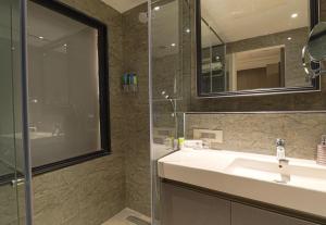 古尔冈AIR by Ahuja Residences的一间带水槽和玻璃淋浴的浴室