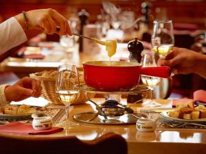 迈恩费尔德瑞士海蒂酒店的餐桌上用红锅做饭的人
