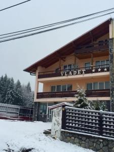 普雷代亚尔Pensiunea Vladet-的雪上标有标志的建筑