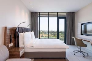 马普托马普托丽笙酒店的一间卧室配有一张床、一张书桌和一个窗户。