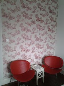 默兹河畔凡尔登La Maison Mirabeau的墙上有两张红色的椅子和一张桌子