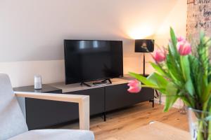 吕讷堡Nicolai Suite - Schrangen-Suites-1389的客厅配有餐桌上的平面电视