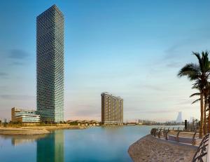 吉达Shangri-La Jeddah的一座高高的建筑和棕榈树的城市天际线