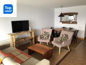 普孔Depto. orilla de lago Villarrica的客厅配有沙发、椅子和电视