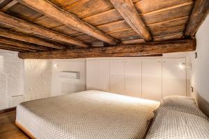 罗马Casa Vantaggio的卧室设有白色的床和木制天花板。