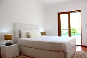 阿马多拉Damaia Apartment的白色的卧室设有一张大床和一个窗户
