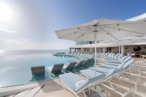 坎昆Sun Palace - All Inclusive Adults Only的一个带椅子和遮阳伞的游泳池以及大海
