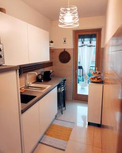 洛科罗通多Deluxe Alba的厨房配有白色橱柜、水槽和窗户。