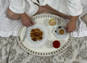 罗马Casa Mia Vaticano Guest House的床上的人,有盘子的食物和一杯咖啡