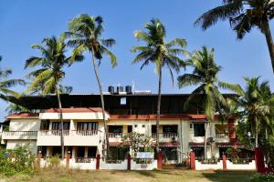 坎多林SHANU'S SEASIDE INN - A Guesthouse, 100 metres to Candolim Beach的一座棕榈树建筑