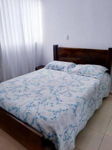 拉特瓦伊达Apartamento amoblado en La Tebaida, Quindio的一间卧室配有一张带蓝色和白色棉被的床